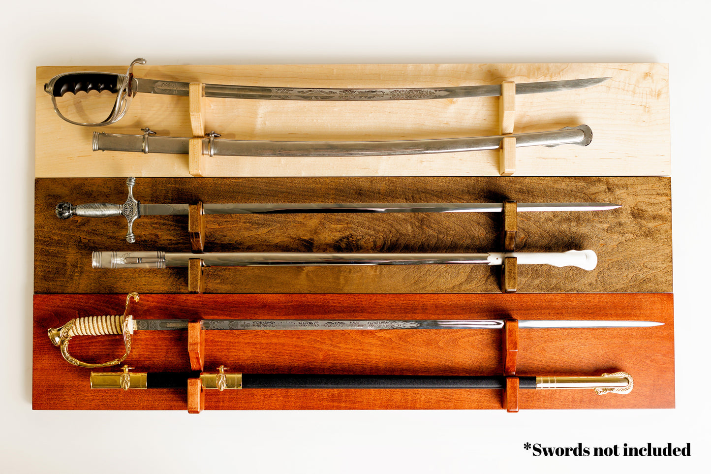 Three Universal Sword Displays showcasing the available hardwood finishes: light Maple, dark Walnut, and classic Cognac.
